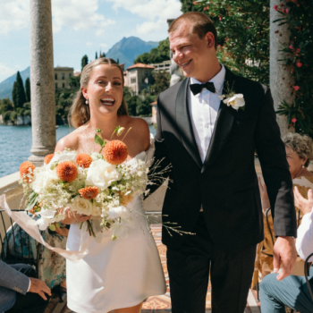 Groom wearing a black wool dinner suit at an intimate Lake Como wedding, sunny Italian villa landscape in the background.