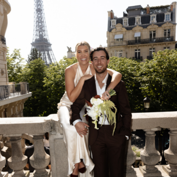Bride and groom posing with the Eiffel Tower behind them, groom in a brown wool suit during a Paris destination wedding.