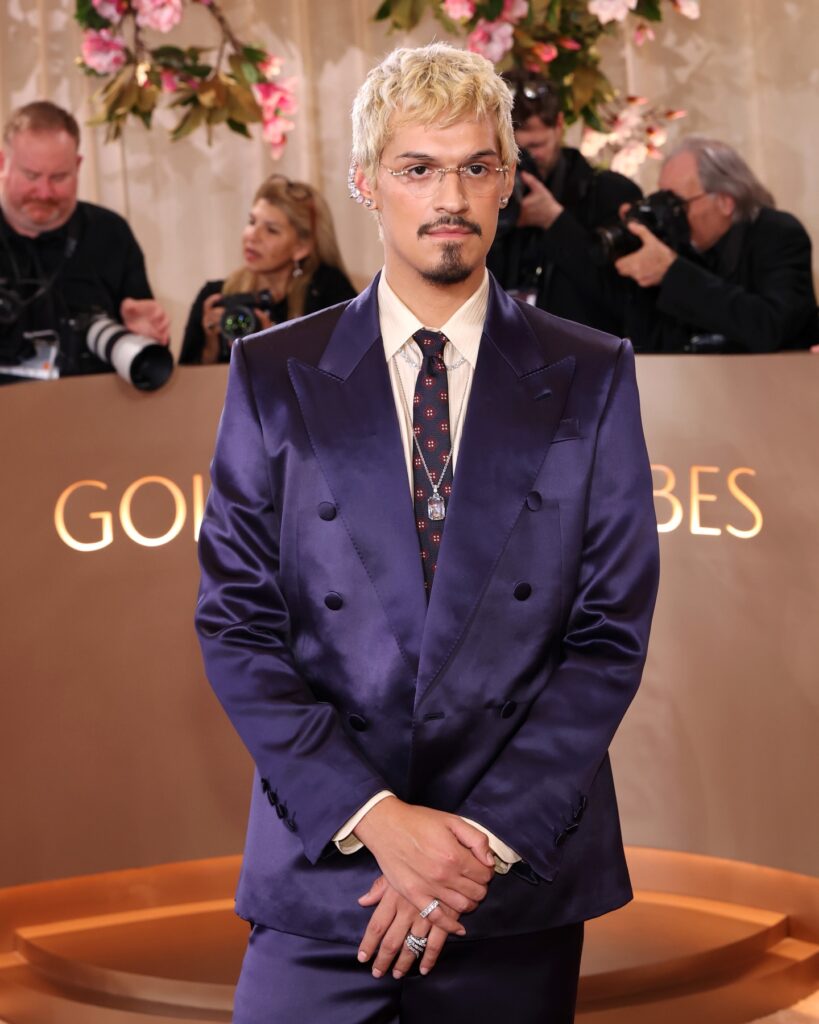 Musician Omar Apollo at the 2026 Golden Globes wearing a blue satin dinner suit and a retro printed neck tie